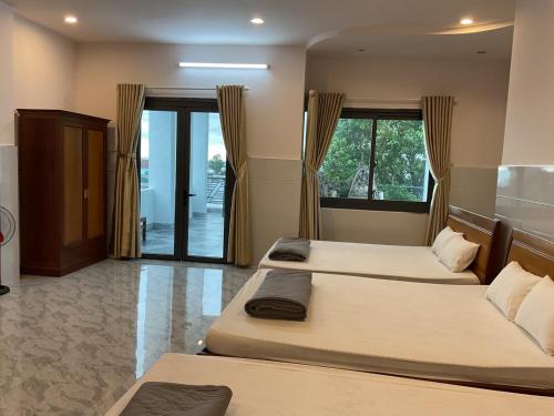 邦美蜀Hoàng Linh Hotel的一间带两张床的卧室和一扇窗户的门