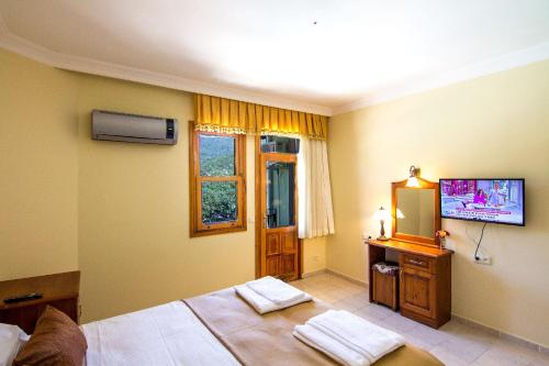 卡亚克Yeşilkaya Hotel的卧室配有一张床,墙上配有电视。