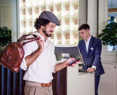 马德里里贾纳酒店的拿着一个袋子看手机的人