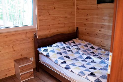 HartowiecLubkowa chata的木制客房的一张小床,设有窗户