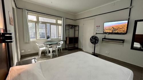 瓜鲁雅Suíte n° 03 - Praia das Pitangueiras的客房设有1张床、1张桌子和1台电视。