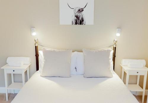 奈斯桥Dalnaglar的一张带白色枕头的床和一幅牛的照片