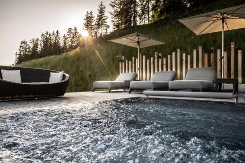 阿尔卑斯休斯山施慕恩酒店的木制甲板上的带椅子和遮阳伞的热水浴池
