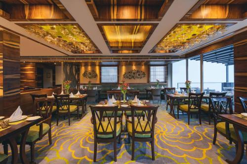 西姆拉Welcomhotel by ITC Hotels, Shimla的用餐室设有桌椅和窗户。