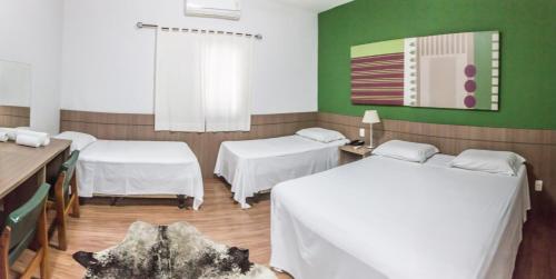 陶巴特萨玛拜亚商务酒店的配有绿色墙壁和白色床单的客房内的两张床