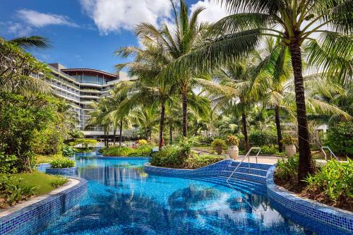 富国Best Western Premier Sonasea Phu Quoc的酒店前方的棕榈树游泳池