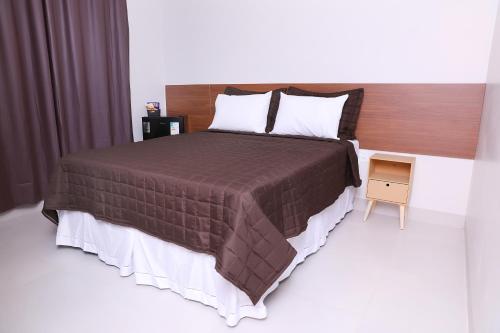 QuirinópolisHotel Borges的一间卧室配有一张大床和一个床头柜