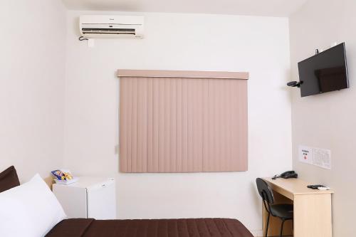 QuirinópolisHotel Borges的客房设有一张床和带电视的窗户。