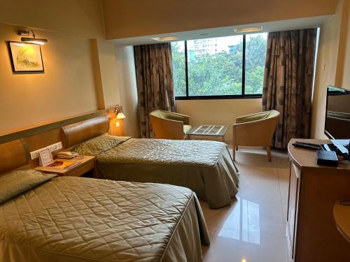 浦那Hotel Ashirwad的酒店客房设有两张床和电视。