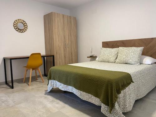 贝纳卢普-卡萨斯维耶哈斯Suites Benalup Centro的一间卧室配有一张床和一张黄色椅子