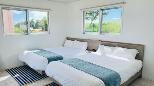 宫古岛Miyako Blue Villa Kugai的带2扇窗户的客房内的2张床