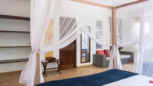 江比阿Raha Lodge Zanzibar Boutique Hotel的卧室配有带白色窗帘的天蓬床