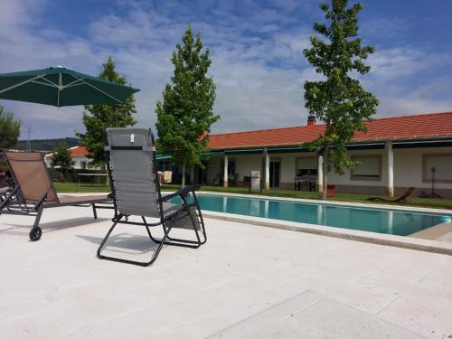 科维良Quinta Lourena - Casa do Caseiro的游泳池旁的一对椅子和一把遮阳伞