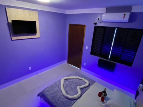 坎皮纳斯Chateau Motel Campinas的紫色的客房配有一张床和电视