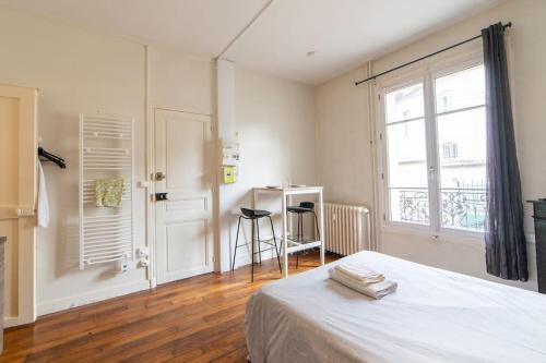 欧塞尔LA BELLE PAUSE - Studio Auxerre proche parking的一间卧室配有一张床、一个窗口和一张书桌
