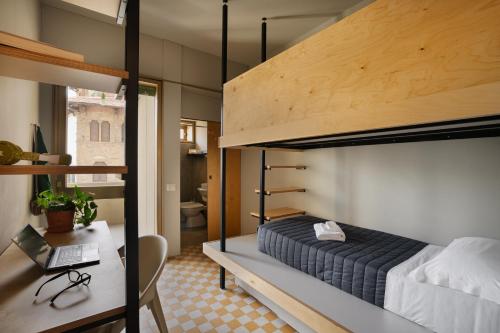 佛罗伦萨'RE-Dama Hostel的一间卧室配有一张双层床和一张带笔记本电脑的书桌