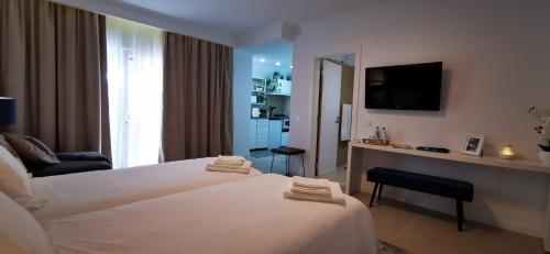克洛伊奥斯Quarto Duplo com Kitchenette, WC e Pátio privativo的酒店客房设有白色的床和电视。