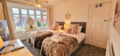 斯凯格内斯Beresford Cottage的配有窗户和书桌的客房内的两张床
