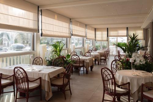 利多迪卡马约雷里维埃拉大酒店的餐厅设有白色的桌椅和窗户。