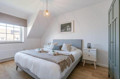 米德尔克尔克Modern house JULIE with spacious garden and garage的卧室设有一张白色大床和一扇窗户。