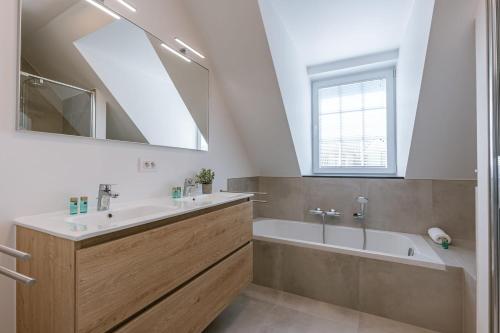 米德尔克尔克Modern house JULIE with spacious garden and garage的一间带水槽、浴缸和镜子的浴室