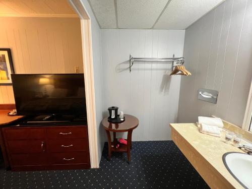 麦基诺城美国精品旅馆 - 湖景的一间带水槽的浴室、一台电视和一张桌子