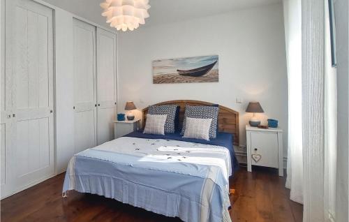 马雷讷Amazing Home In Marennes With Private Swimming Pool, Can Be Inside Or Outside的一间卧室配有一张带蓝色床单和吊灯的床。