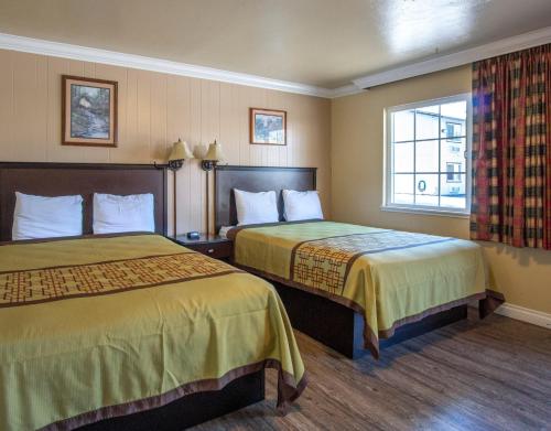 BurneyCharm Motel & Suites的酒店客房设有两张床和窗户。