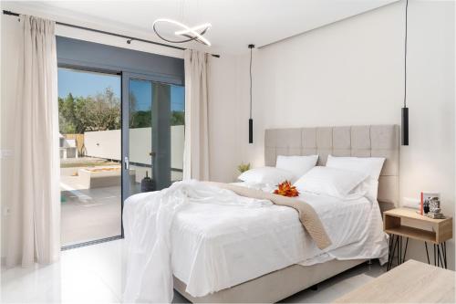 扎金索斯镇Ionian Escape的卧室配有白色的床和滑动玻璃门