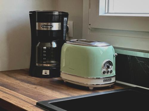亚历山德鲁波利斯COMFY DEN by Cozy Stories的咖啡壶旁的柜台上放置绿色烤面包机