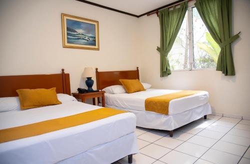 圣萨尔瓦多Hotel Villa Serena San Benito的一间卧室设有两张床和窗户。
