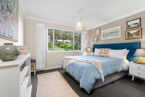 海姆斯海滩24 Hyam Rd Hyams Beach的一间卧室设有蓝色的床和窗户。