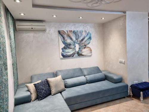 洛泽内茨Oazis resort lux vip apartament的客厅配有蓝色沙发和绘画作品