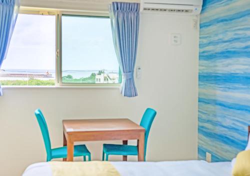 宫古岛ヴィラアマルフィ パームスプリングス宮古島リゾート的窗户客房内的桌椅