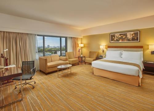 马尼拉Holiday Inn & Suites Makati, an IHG Hotel的大型酒店客房,配有一张床和一张书桌