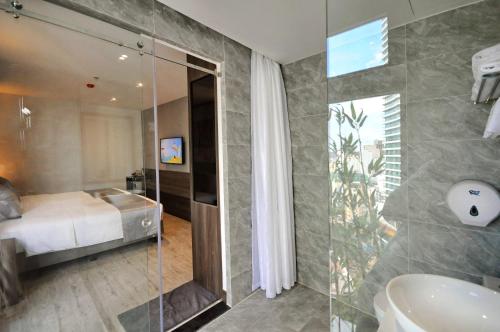 芽庄Ivy Hotel Nha Trang的配有床、淋浴和盥洗盆的浴室