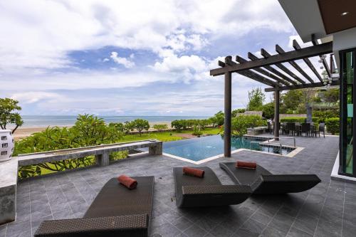 华欣BeachFront Modern 4 Bedroom Pool Villa RV的一个带游泳池和凉亭的户外庭院