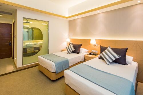 新加坡新加坡共和国游艇俱乐部酒店的酒店客房,设有两张床和镜子