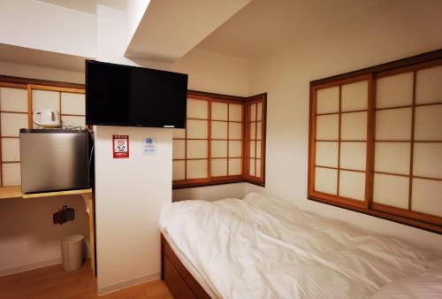 东京Hostel Belle Via Tokyo的一间房间,配有一张床和墙上的电视
