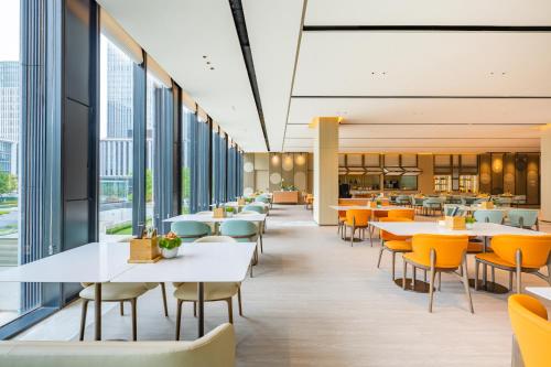 上海上海世博逸衡酒店的一间设有桌椅和窗户的自助餐厅