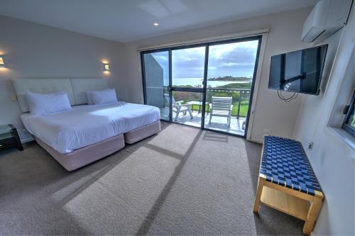 比舍诺钻石岛度假村＆比舍诺企鹅展的一间卧室设有一张床、一台电视和一个阳台。