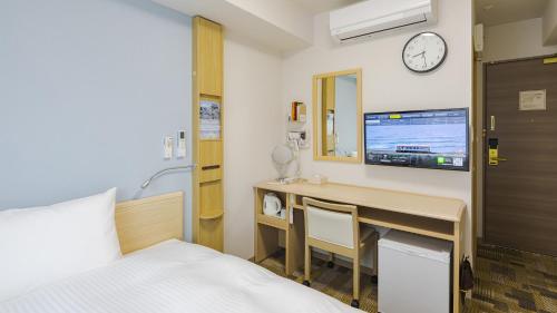 周南市Toyoko Inn Tokuyama-eki Kita-guchi的酒店客房设有一张床、一张书桌和一台电视机。