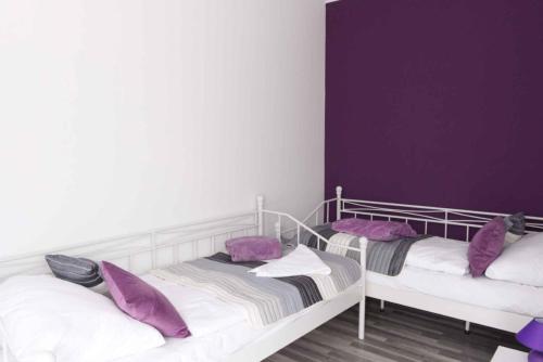 比克Apartments in Bük - Nordtransdanubien 44085的紫色墙壁客房的两张床
