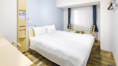 横滨Toyoko Inn Futamatagawa-eki Kita-guchi的卧室配有一张白色的大床和一张桌子