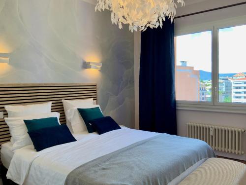 安锡Le 21 Favre, Hyper centre, 70 m², 2 chambres的一间卧室配有两张带蓝色枕头和吊灯的床。