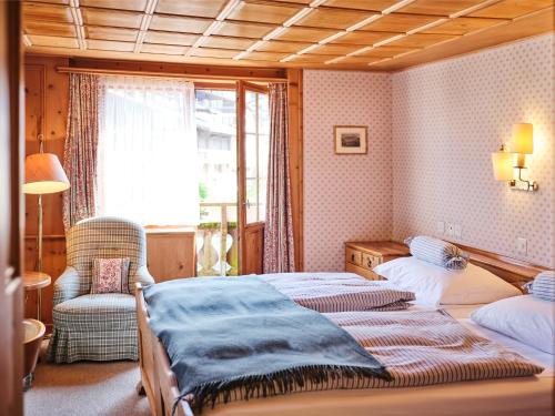 克洛斯特斯Hotel Chesa Grischuna的一间卧室设有两张床、一把椅子和一个窗户。
