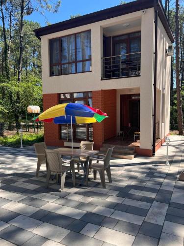 谢赫维蒂利Villa Premium Shekvetili的桌椅和遮阳伞位于房子前