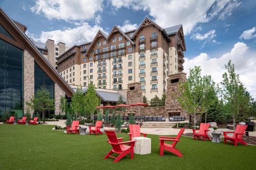 奥罗拉Gaylord Rockies Resort & Convention Center的一座大建筑,在草地上摆放着红色的桌椅