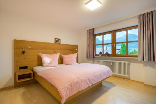 奥伯斯特多夫Ferienwohnung Alpentraum-Panorama Chalet的一间卧室配有带粉红色枕头的床和窗户。