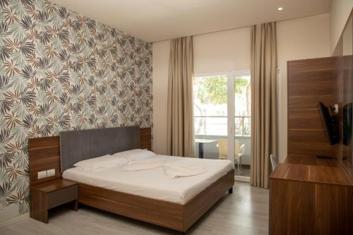 都拉斯迪拉酒店的一间卧室设有一张床、一台电视和一个窗口。